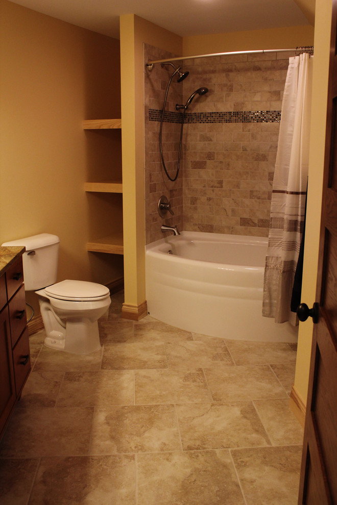 Photo of a medium sized traditional ensuite bathroom in Other with shaker cabinets, medium wood cabinets, an alcove bath, a shower/bath combination, beige tiles, stone tiles, granite worktops, a two-piece toilet, beige walls, travertine flooring and a submerged sink.