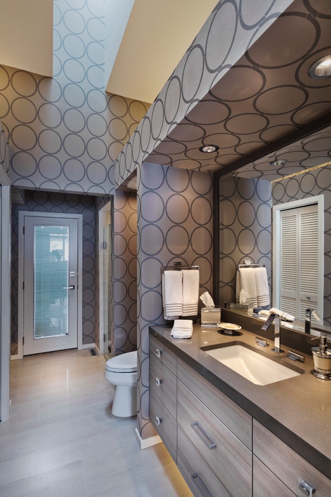 На фото: огромная ванная комната в современном стиле с врезной раковиной, плоскими фасадами, коричневыми стенами, светлыми деревянными фасадами, столешницей из гранита, полом из керамогранита, душевой кабиной и серой столешницей