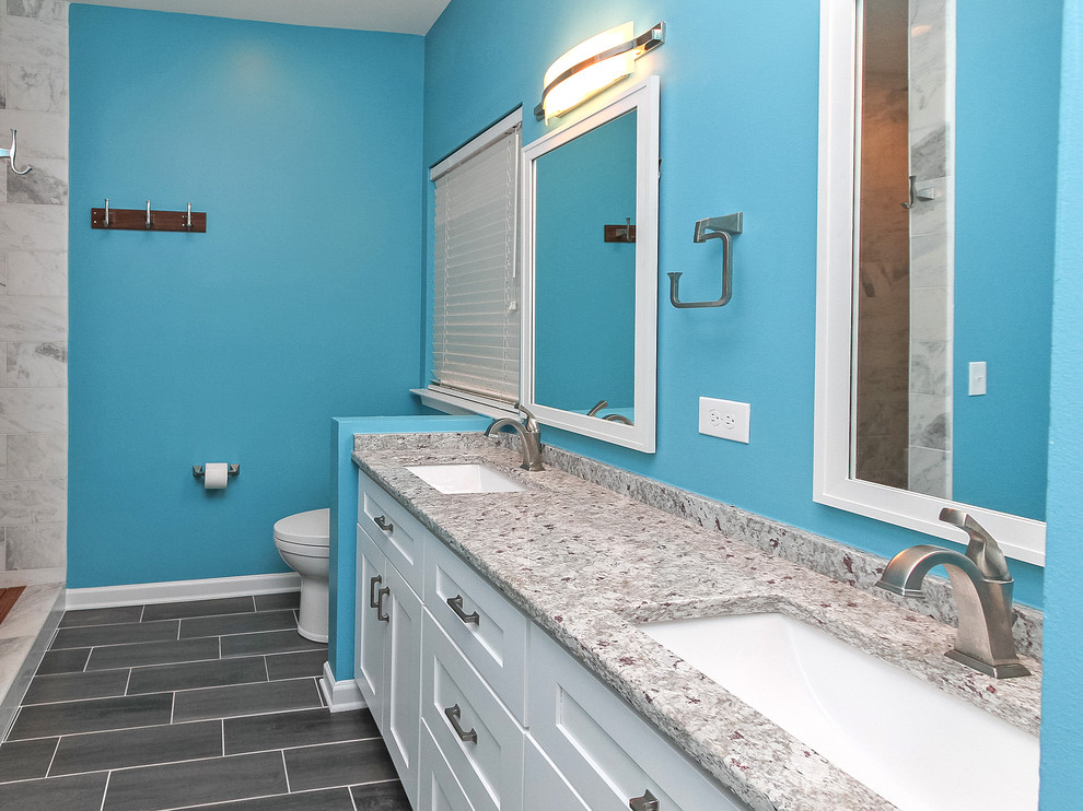 シャーロットにあるお手頃価格の中くらいなビーチスタイルのおしゃれなマスターバスルーム (シェーカースタイル扉のキャビネット、白いキャビネット、オープン型シャワー、分離型トイレ、茶色いタイル、セラミックタイル、青い壁、セラミックタイルの床、アンダーカウンター洗面器、御影石の洗面台) の写真