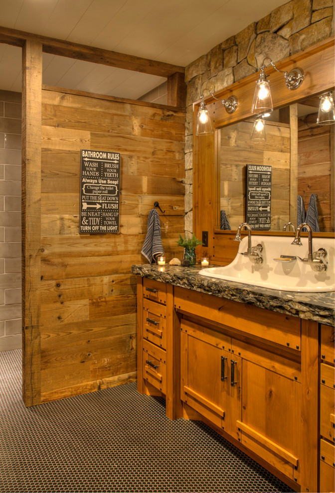 Foto på ett mellanstort rustikt svart badrum för barn, med skåp i mellenmörkt trä, ett avlångt handfat, klinkergolv i porslin, granitbänkskiva, svart golv och luckor med infälld panel