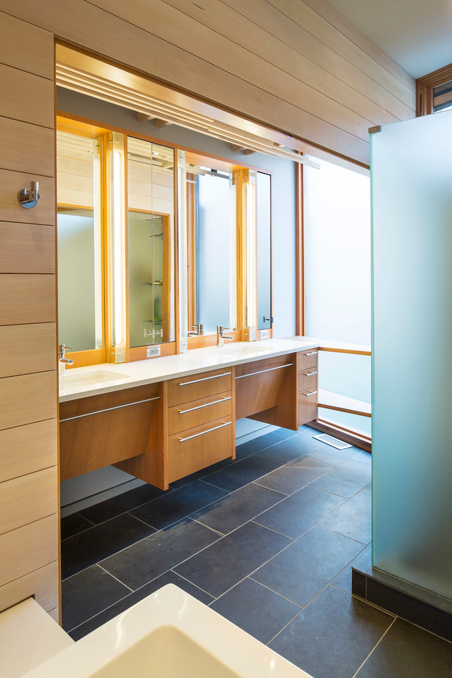 Photo of a medium sized modern ensuite bathroom in Minneapolis with flat-panel cabinets, light wood cabinets, a freestanding bath, a corner shower, grey tiles, stone tiles, slate flooring, an integrated sink and engineered stone worktops.