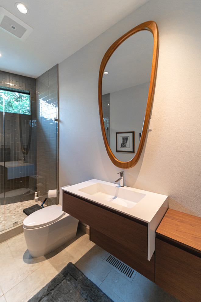 Idéer för ett mellanstort modernt vit badrum med dusch, med släta luckor, bruna skåp, en dusch i en alkov, en toalettstol med hel cisternkåpa, grå kakel, glaskakel, klinkergolv i keramik, ett integrerad handfat, bänkskiva i akrylsten, beiget golv och dusch med gångjärnsdörr