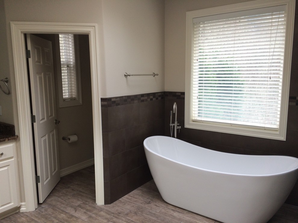 Inspiration för mellanstora moderna en-suite badrum, med luckor med upphöjd panel, vita skåp, ett fristående badkar, grå kakel, porslinskakel, vita väggar, mellanmörkt trägolv, granitbänkskiva och grått golv