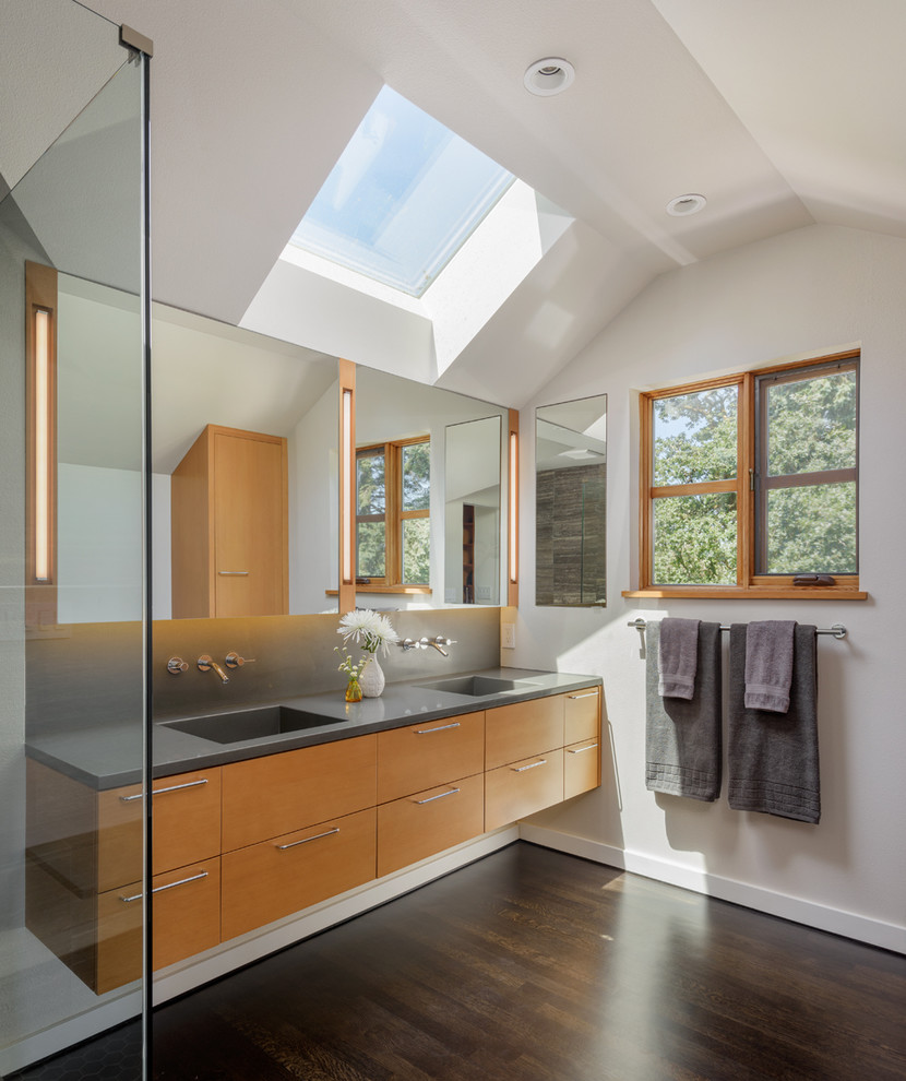 Immagine di una stanza da bagno contemporanea con ante lisce, ante in legno chiaro, parquet scuro e lavabo integrato
