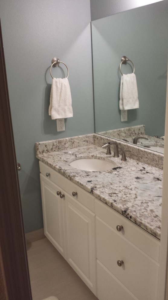 Medium sized contemporary ensuite bathroom in Boise with beaded cabinets, white cabinets, blue walls, porcelain flooring, a submerged sink and granite worktops.