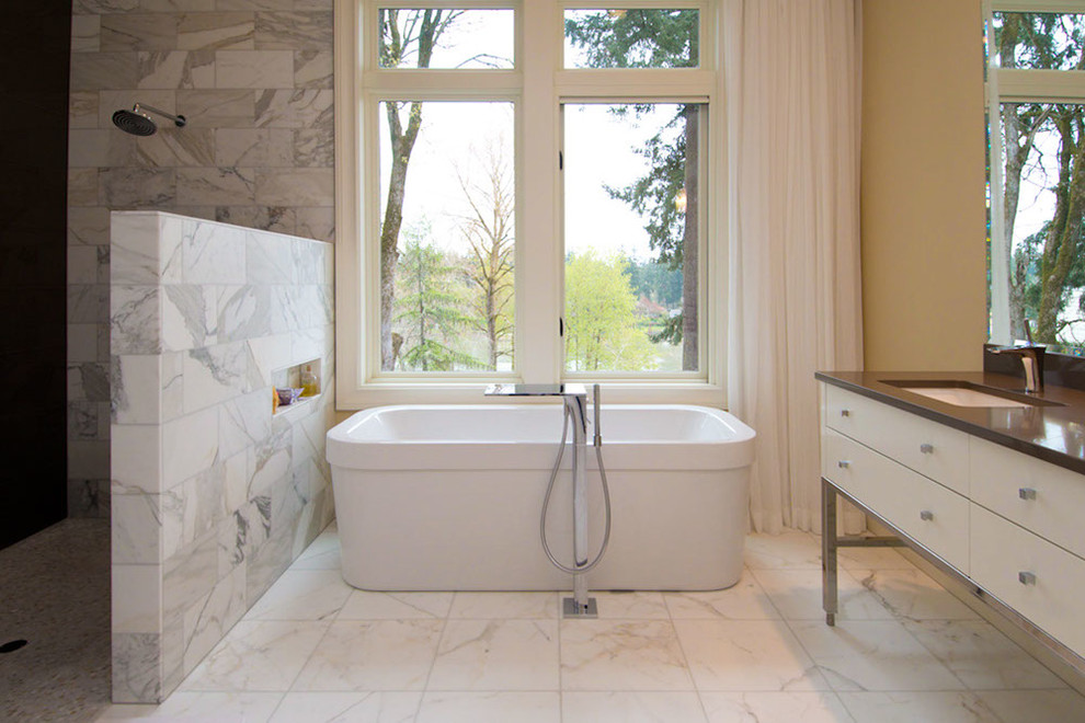 Cette image montre une salle de bain design avec une baignoire indépendante, une douche ouverte, aucune cabine et une fenêtre.