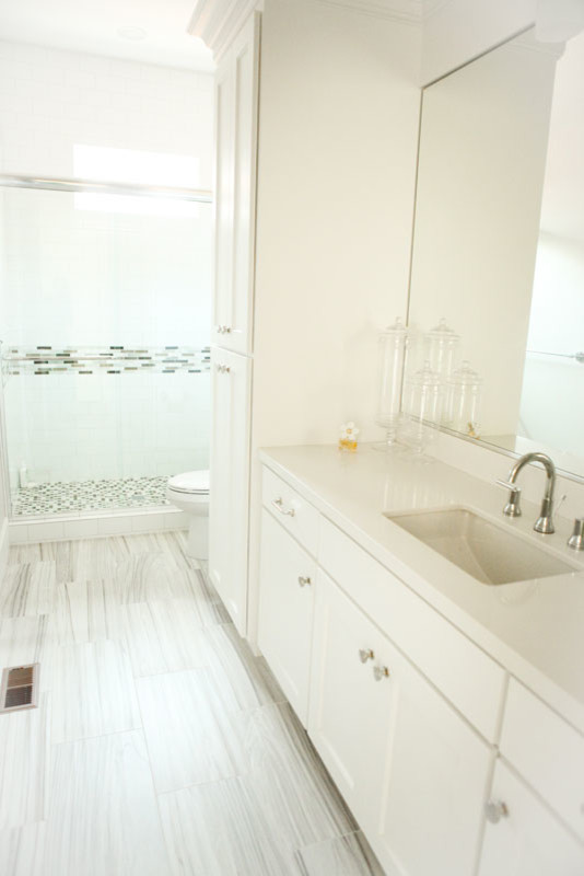 Idéer för mellanstora vintage badrum med dusch, med luckor med infälld panel, vita skåp, en hörndusch, en toalettstol med separat cisternkåpa, grå kakel, vit kakel, stickkakel, vita väggar, klinkergolv i porslin, ett undermonterad handfat och bänkskiva i akrylsten