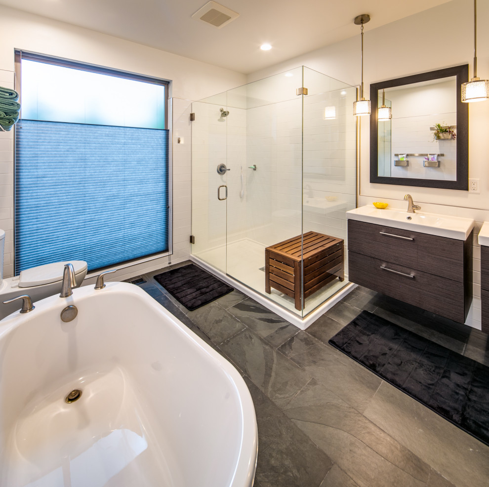 Photo of a medium sized contemporary ensuite bathroom in Seattle with flat-panel cabinets, grey cabinets, a freestanding bath, a built-in shower, a one-piece toilet, white tiles, metro tiles, grey walls, slate flooring, an integrated sink, quartz worktops, black floors, a hinged door and white worktops.