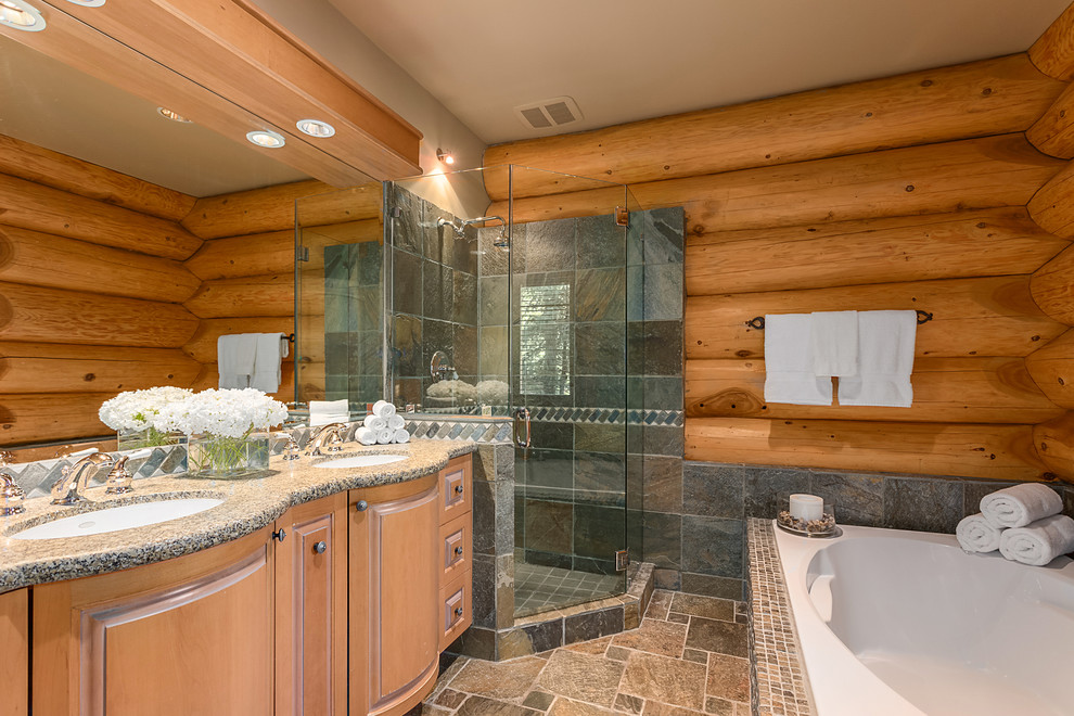 Foto di una stanza da bagno rustica con ante in legno chiaro, vasca ad angolo, piastrelle grigie e pareti marroni