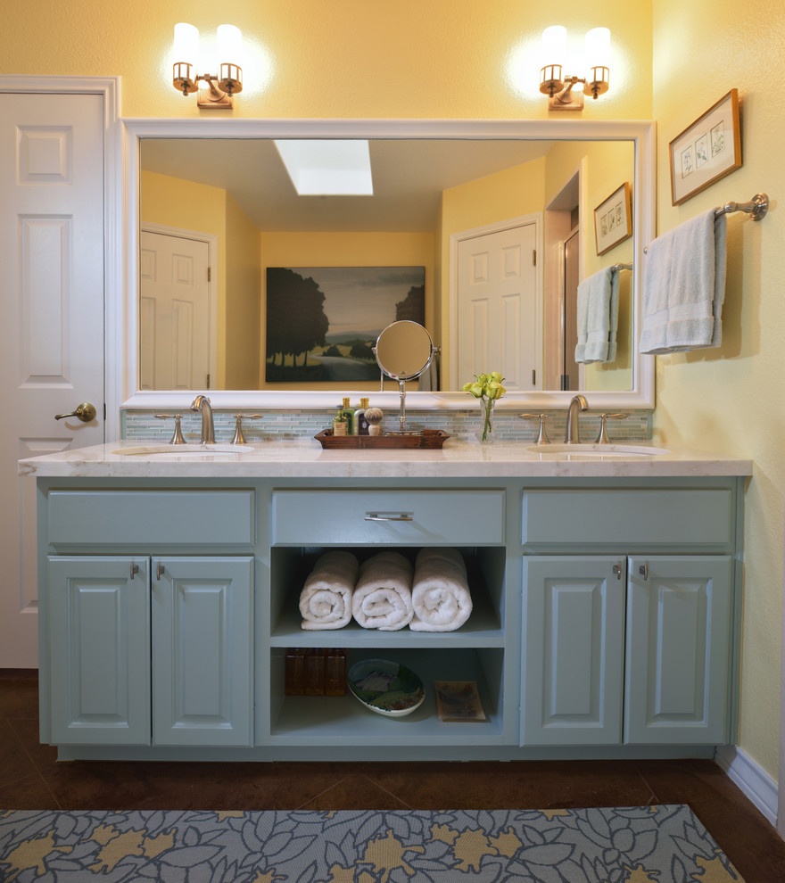 Inredning av ett klassiskt mellanstort en-suite badrum, med ett undermonterad handfat, luckor med upphöjd panel, blå skåp, blå kakel, marmorbänkskiva, en dusch i en alkov, en toalettstol med separat cisternkåpa, gula väggar och betonggolv