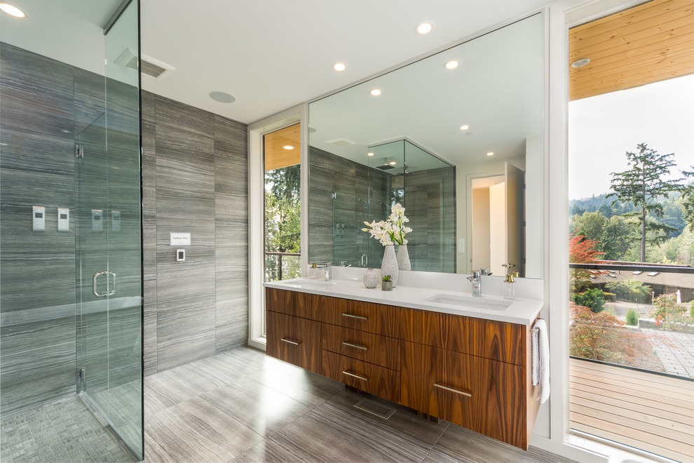 Cette photo montre une salle de bain principale tendance en bois brun avec un placard à porte plane, une douche à l'italienne, un carrelage gris, un lavabo encastré, un sol gris et une cabine de douche à porte battante.