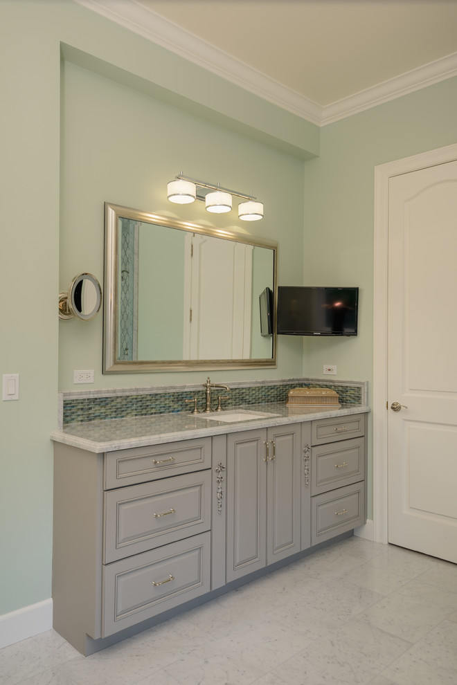 Example of a large classic 3/4 beige tile travertine floor and beige floor bathroom design in Los Angeles with raised-panel cabinets, green cabinets, a two-piece toilet, beige walls, a vessel sink and marble countertops