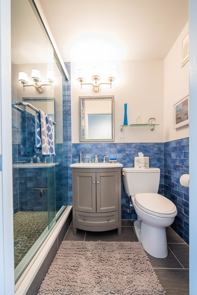 Réalisation d'une salle d'eau méditerranéenne avec un placard en trompe-l'oeil, des portes de placard grises, WC séparés, un carrelage bleu, un carrelage en pâte de verre, un lavabo encastré, un plan de toilette en quartz, un sol gris et un plan de toilette blanc.