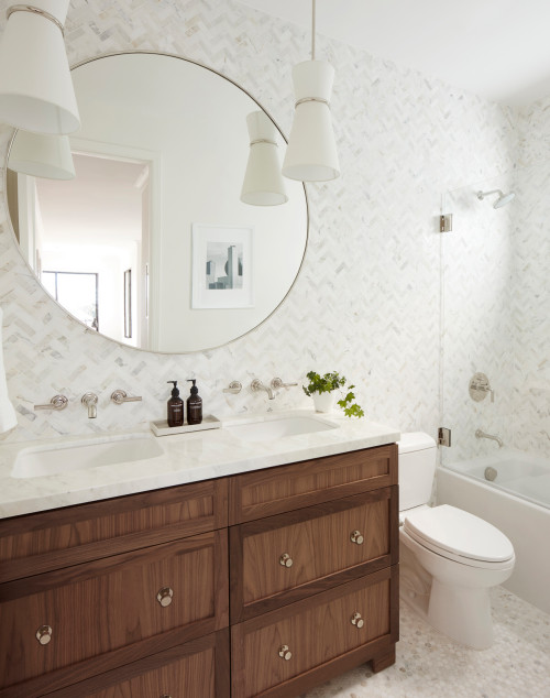 Stylish wooden bathroom cabinets with marble countertop, double sinks, round mirror, and modern white tile wall in a bright contemporary bathroom