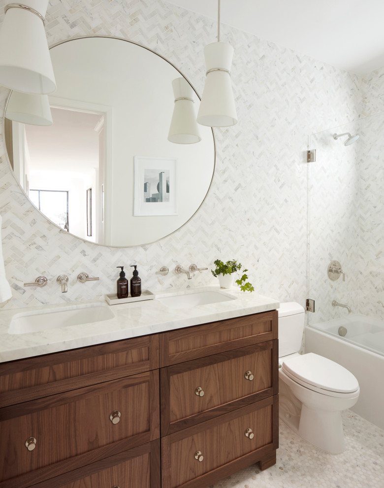 Пример оригинального дизайна: ванная комната среднего размера в стиле неоклассика (современная классика) с фасадами в стиле шейкер, темными деревянными фасадами, ванной в нише, душем над ванной, раздельным унитазом, белой плиткой, мраморной плиткой, белыми стенами, мраморным полом, душевой кабиной, врезной раковиной, мраморной столешницей, белым полом, душем с распашными дверями, белой столешницей, тумбой под две раковины и встроенной тумбой
