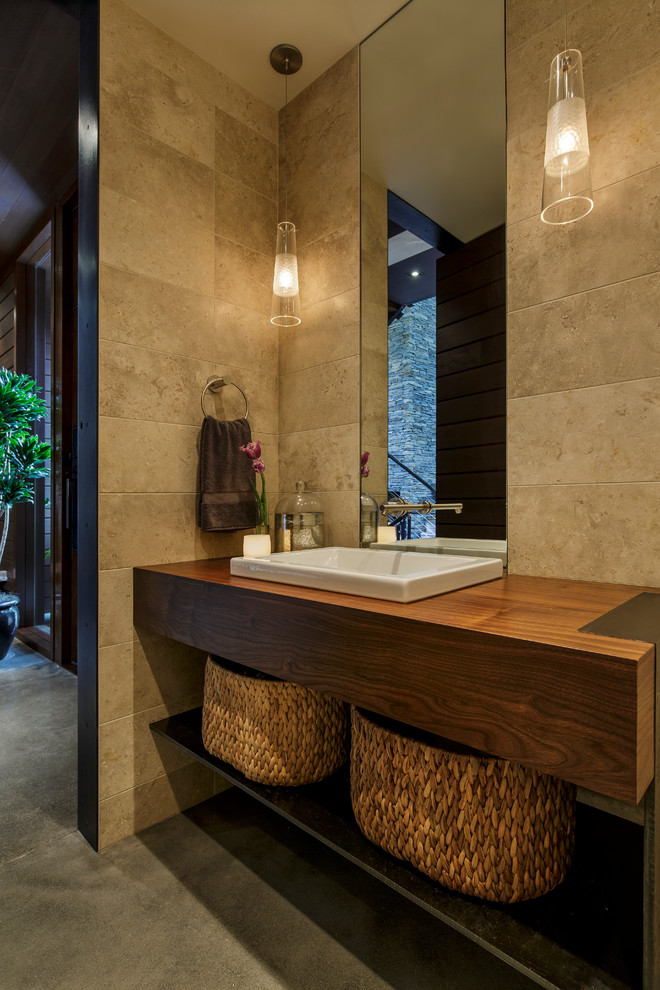 Идея дизайна: большая ванная комната в современном стиле с бежевой плиткой, бетонным полом, накладной раковиной, столешницей из дерева, открытыми фасадами, темными деревянными фасадами, керамогранитной плиткой, коричневыми стенами, серым полом и зеркалом с подсветкой
