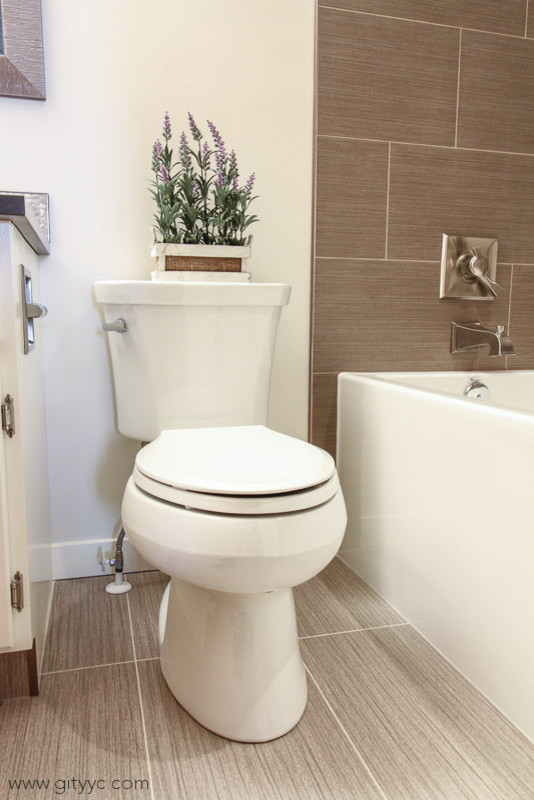 Inredning av ett klassiskt litet badrum med dusch, med luckor med upphöjd panel, ett platsbyggt badkar, en toalettstol med separat cisternkåpa, brun kakel, keramikplattor, vita väggar, vinylgolv, ett undermonterad handfat, bänkskiva i kvartsit och vita skåp