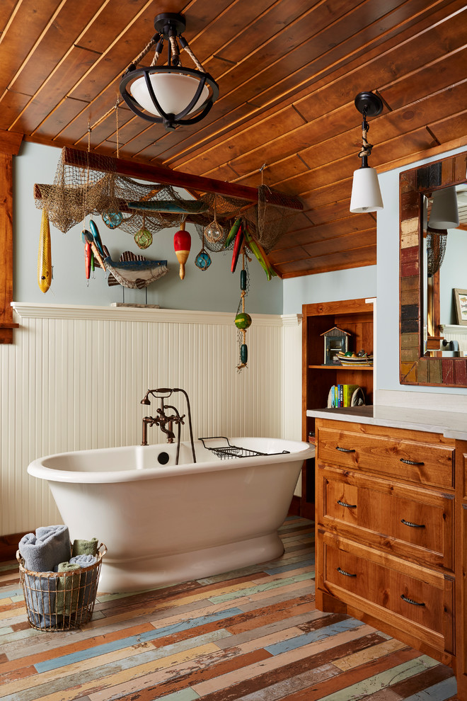 Imagen de cuarto de baño principal rural de tamaño medio con puertas de armario de madera oscura, bañera exenta, paredes azules, encimera de granito, suelo multicolor, baldosas y/o azulejos azules, suelo de madera pintada y armarios con paneles empotrados