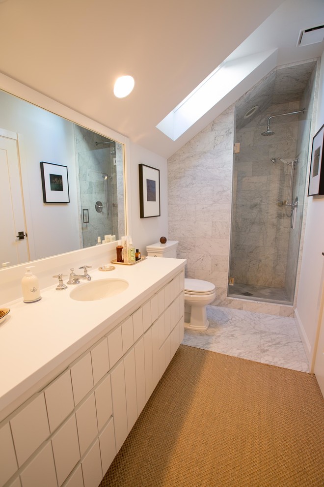 Ispirazione per una stanza da bagno con doccia stile americano di medie dimensioni con lavabo sottopiano, ante lisce, ante bianche, top in superficie solida, doccia aperta, WC monopezzo, pareti bianche e pavimento in marmo