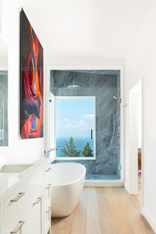 Modernes Badezimmer mit Schrankfronten im Shaker-Stil, weißen Schränken, freistehender Badewanne, weißer Wandfarbe, braunem Holzboden, Unterbauwaschbecken, braunem Boden und weißer Waschtischplatte in Vancouver