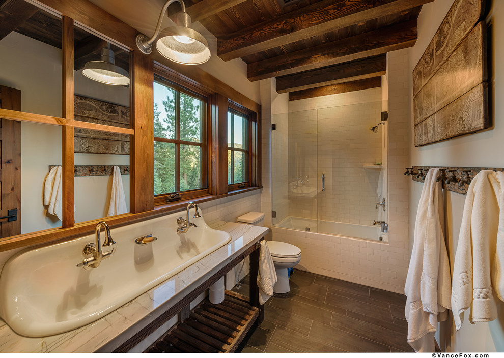 Klassisk inredning av ett mellanstort badrum, med ett avlångt handfat, granitbänkskiva, ett platsbyggt badkar, en dusch/badkar-kombination, en toalettstol med hel cisternkåpa, vit kakel, porslinskakel, beige väggar och klinkergolv i porslin