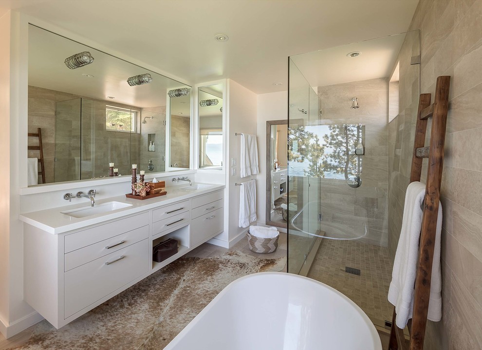 Inspiration for a large contemporary ensuite bathroom in San Francisco with flat-panel cabinets, white cabinets, a freestanding bath, a corner shower, beige tiles, ceramic tiles, beige walls, ceramic flooring, a built-in sink, grey floors and a hinged door.