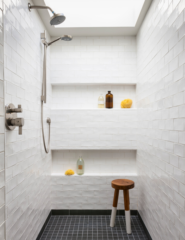 Inredning av ett maritimt badrum, med en dusch i en alkov, vit kakel, tunnelbanekakel, mosaikgolv och svart golv