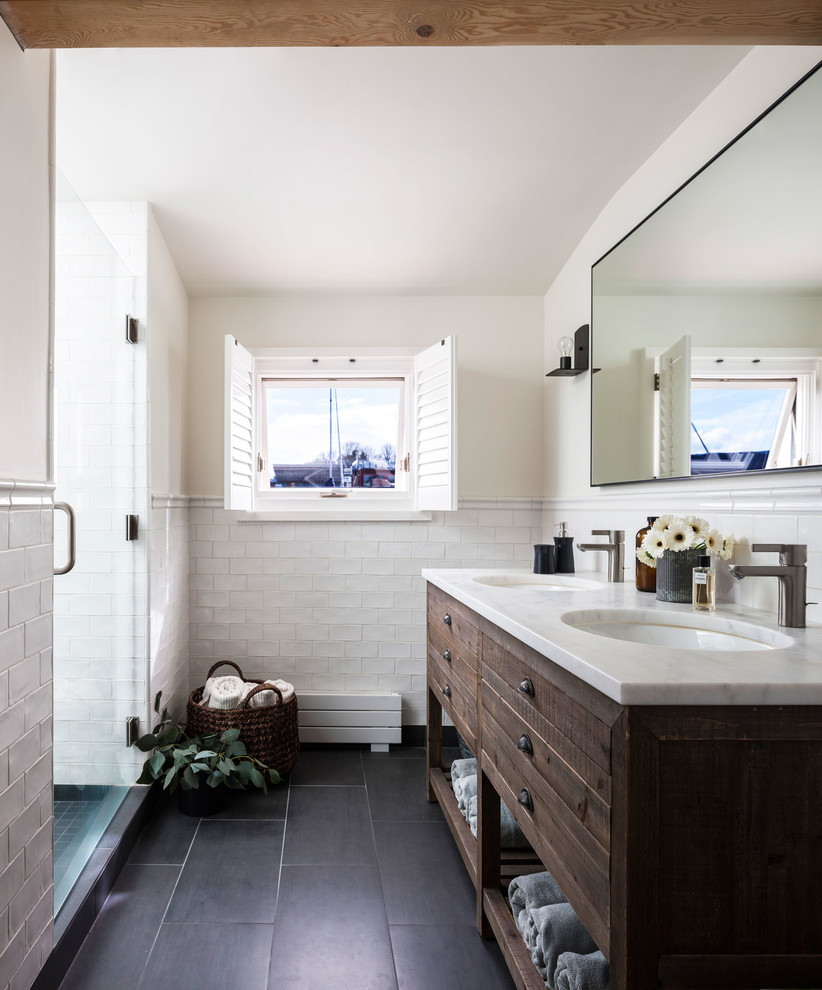 Beach style white tile and subway tile black floor alcove shower photo in Seattle with furniture-like cabinets, dark wood cabinets, white walls, an undermount sink, a hinged shower door and white countertops