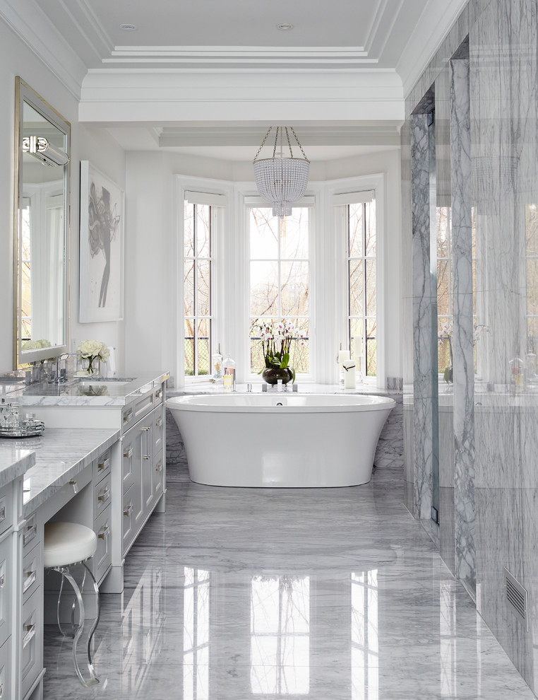 Klassisk inredning av ett grå grått en-suite badrum, med grå skåp, ett fristående badkar, grå kakel, marmorkakel, vita väggar, marmorgolv, ett undermonterad handfat, marmorbänkskiva och grått golv
