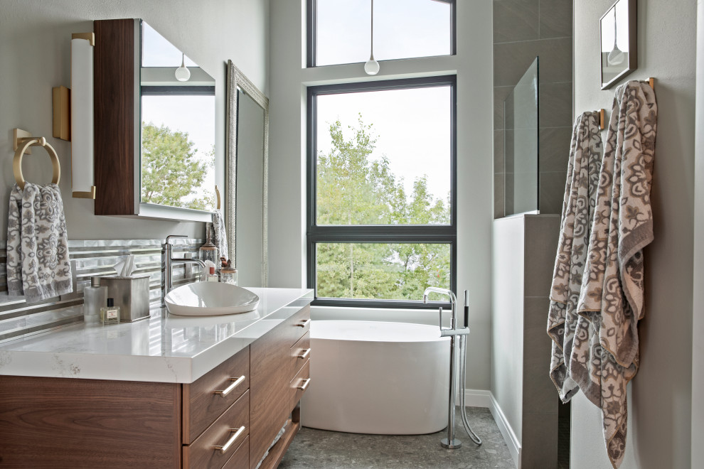 Cette photo montre une salle de bain principale tendance en bois foncé de taille moyenne avec un placard à porte plane, une baignoire indépendante, une douche d'angle, WC à poser, des carreaux de porcelaine, un mur gris, une vasque, un sol gris et aucune cabine.
