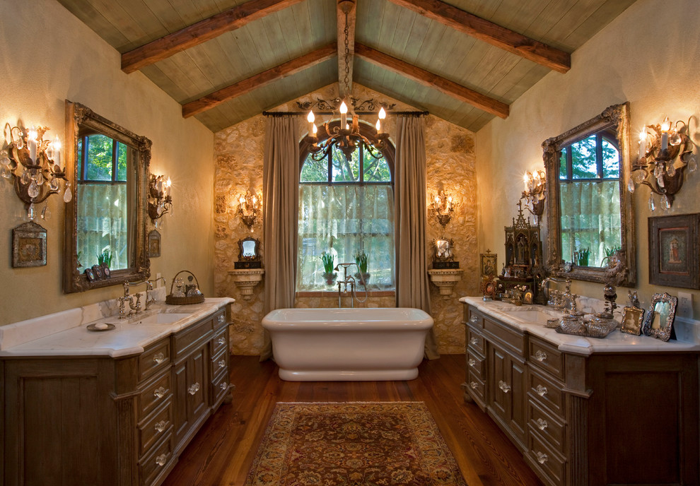 Photo of a large mediterranean ensuite bathroom in Austin with dark wood cabinets and a freestanding bath.