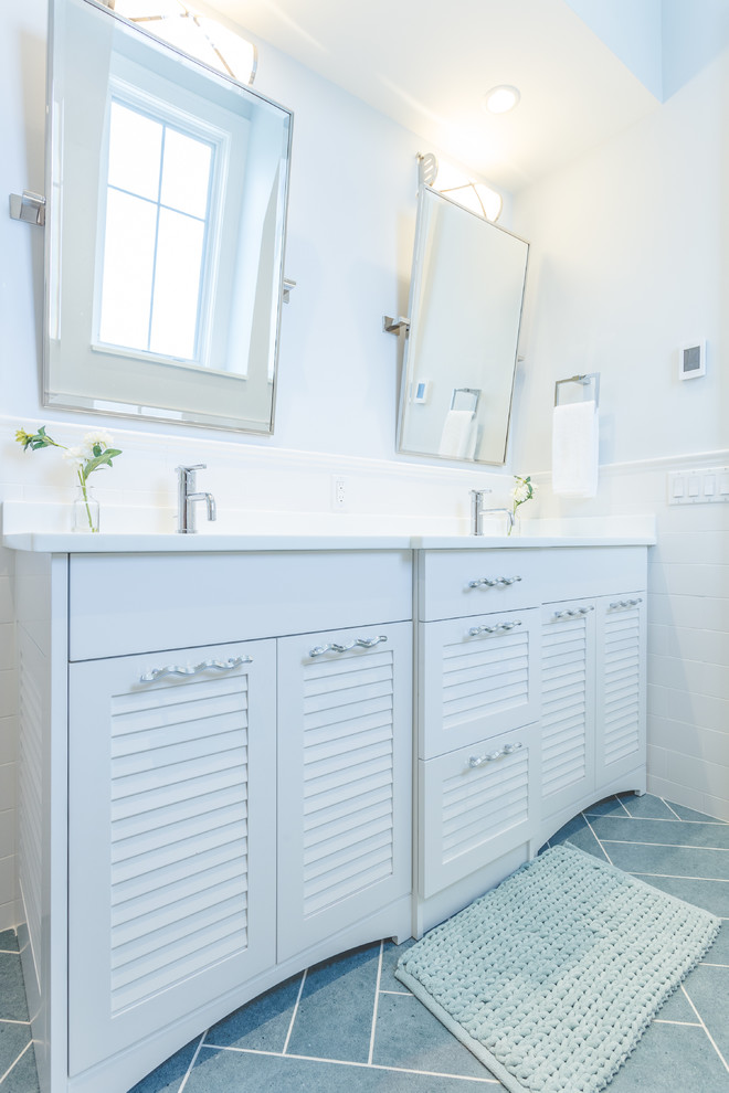 Modern inredning av ett stort badrum för barn, med vita skåp, en öppen dusch, en toalettstol med hel cisternkåpa, grå kakel, blå väggar och ett nedsänkt handfat