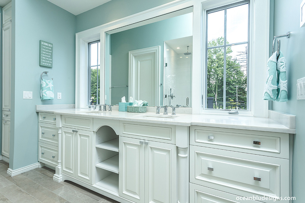 This is an example of a large contemporary ensuite bathroom in New York with white cabinets, a walk-in shower, a one-piece toilet, white tiles, blue walls, marble flooring and a built-in sink.