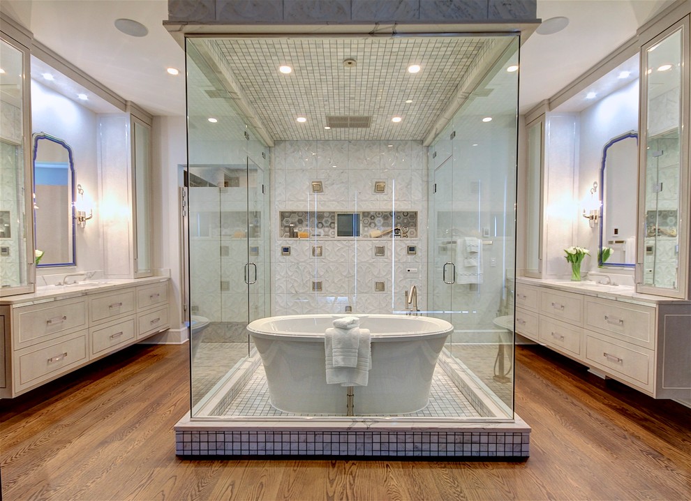 Пример оригинального дизайна: главная ванная комната в стиле неоклассика (современная классика) с фасадами островного типа, серыми фасадами, отдельно стоящей ванной, душевой комнатой, биде, серой плиткой, мраморной плиткой, белыми стенами, паркетным полом среднего тона, врезной раковиной, столешницей из искусственного кварца и душем с распашными дверями