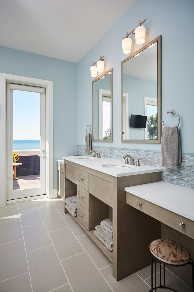 Cette image montre une salle de bain principale marine en bois clair avec un placard sans porte, un carrelage multicolore, mosaïque, un mur bleu et un lavabo encastré.