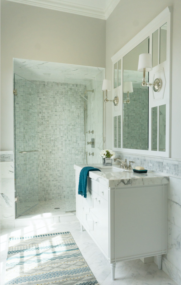 Идея дизайна: большая ванная комната в стиле неоклассика (современная классика) с фасадами островного типа, белыми фасадами, душем в нише, белой плиткой, мраморной плиткой, врезной раковиной, мраморной столешницей, душем с распашными дверями и белой столешницей