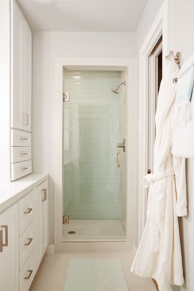 Cette photo montre une salle de bain chic de taille moyenne avec un placard avec porte à panneau encastré, des portes de placard blanches, une douche ouverte, un carrelage beige, un mur beige et un sol en bois brun.