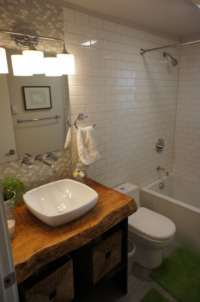 Exemple d'une salle d'eau tendance en bois foncé de taille moyenne avec un placard en trompe-l'oeil, une baignoire en alcôve, un combiné douche/baignoire, WC à poser, un carrelage blanc, un carrelage métro, une vasque, un plan de toilette en bois, un sol gris et une cabine de douche avec un rideau.