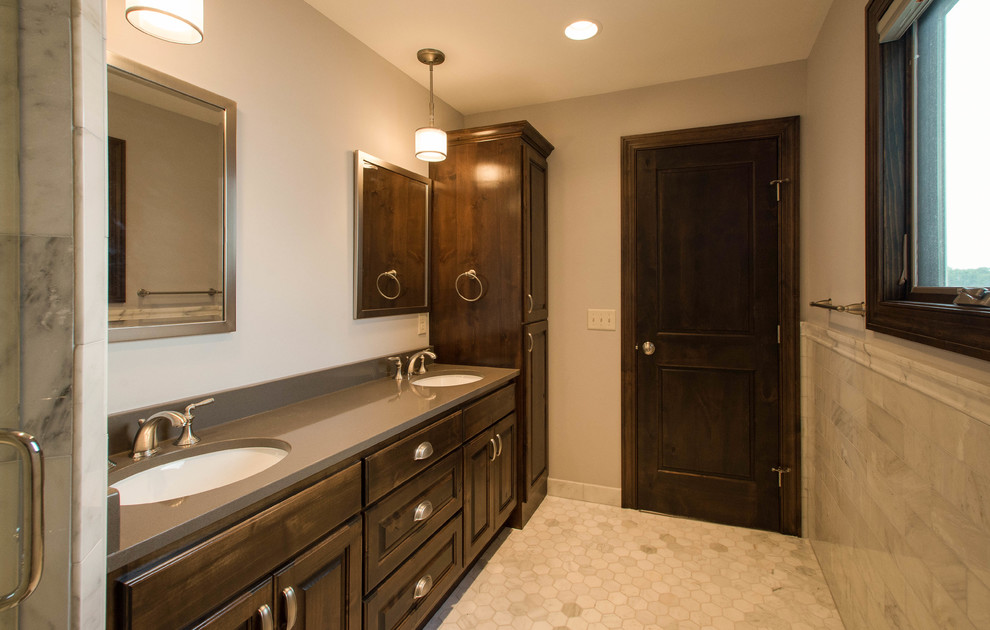 Example of a mid-sized classic white tile and stone tile marble floor corner shower design in Minneapolis with an undermount sink, raised-panel cabinets, dark wood cabinets, quartzite countertops, a two-piece toilet and gray walls