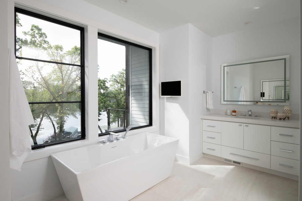 Design ideas for a contemporary ensuite bathroom in Minneapolis with flat-panel cabinets, white cabinets, a freestanding bath, white walls, a submerged sink, beige floors and beige worktops.