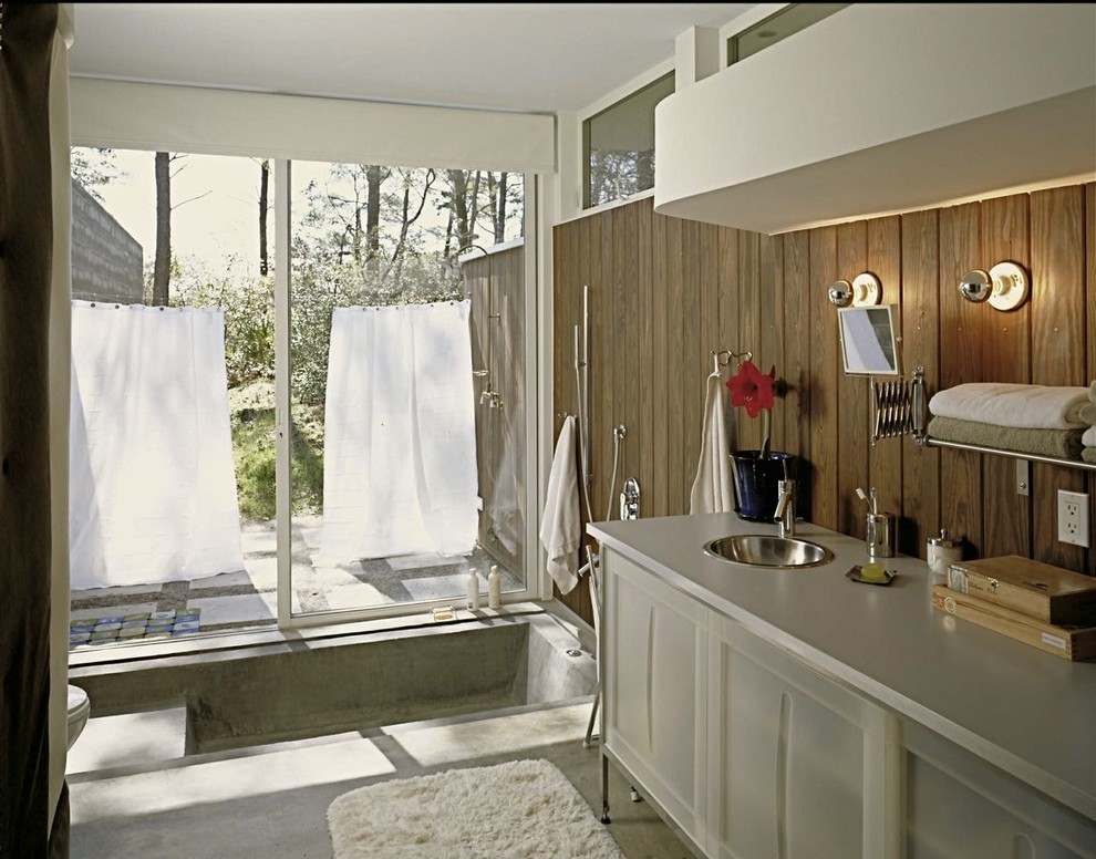 Idee per una piccola stanza da bagno minimalista con lavabo sottopiano, ante grigie, top in laminato, vasca/doccia, WC monopezzo, pareti marroni e pavimento in cemento