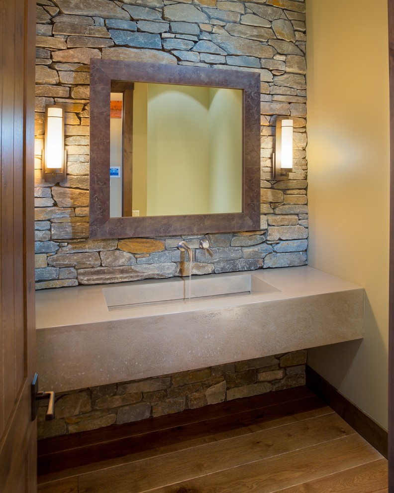 Cette photo montre une salle de bain montagne avec une grande vasque, un plan de toilette en béton et un mur en pierre.