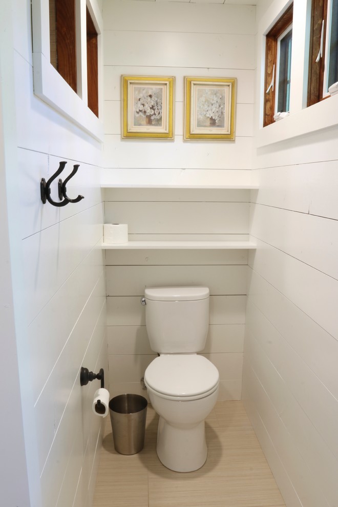 Cette image montre un WC et toilettes rustique en bois brun de taille moyenne avec un placard à porte shaker, un carrelage beige, des carreaux de porcelaine, un mur blanc, un lavabo encastré et un plan de toilette en quartz modifié.