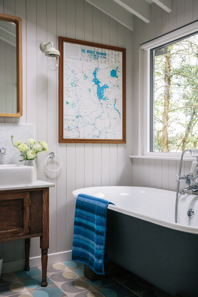 This is an example of a rural bathroom in London with dark wood cabinets, a freestanding bath, grey walls, a vessel sink and shaker cabinets.