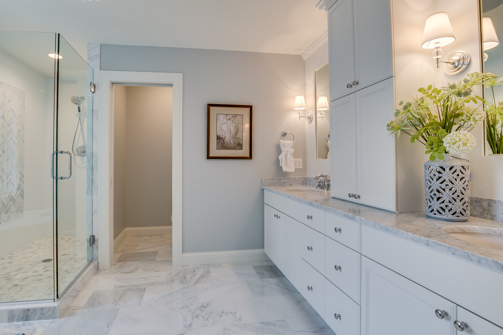 Photo of a large country ensuite bathroom in Minneapolis with recessed-panel cabinets, white cabinets, an alcove shower, a one-piece toilet, grey tiles, grey walls, a submerged sink, grey floors and a hinged door.