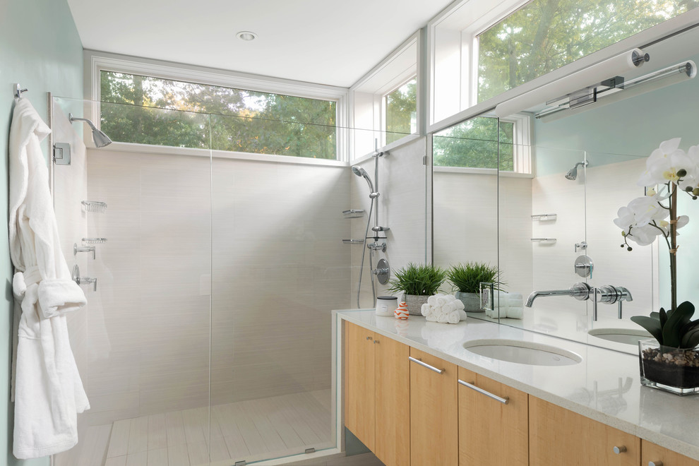 Пример оригинального дизайна: ванная комната в современном стиле с плоскими фасадами, светлыми деревянными фасадами, угловым душем, белой плиткой, зелеными стенами, врезной раковиной, душем с распашными дверями и белой столешницей