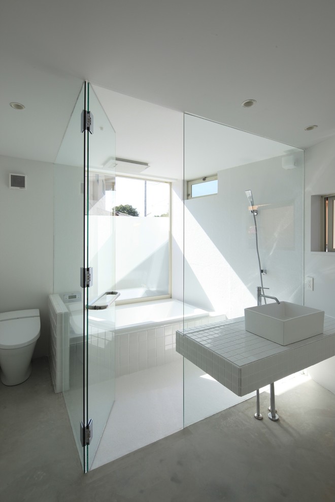 Design ideas for a contemporary ensuite bathroom with an alcove bath, a built-in shower, a one-piece toilet, white tiles, white walls, a vessel sink, tiled worktops and a single sink.