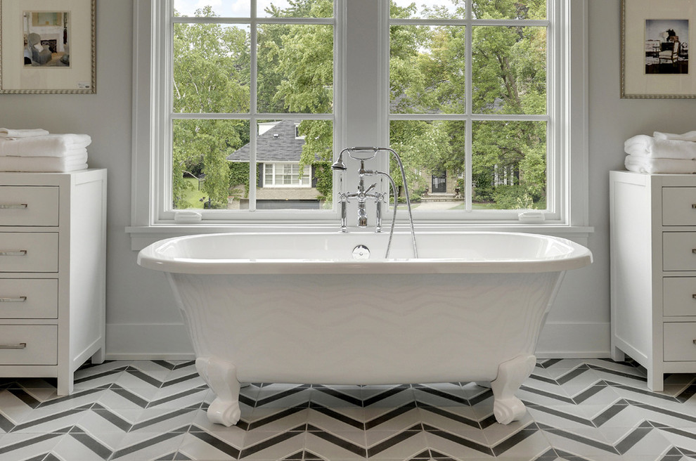 Modelo de cuarto de baño clásico renovado con puertas de armario blancas, bañera con patas, baldosas y/o azulejos multicolor, ventanas y armarios con paneles lisos