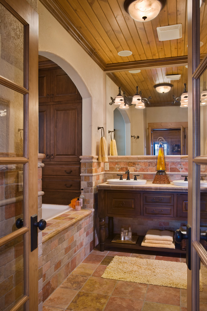 Idéer för stora rustika en-suite badrum, med ett nedsänkt handfat, möbel-liknande, skåp i mörkt trä, kaklad bänkskiva, ett badkar i en alkov, beige kakel, keramikplattor, vita väggar och travertin golv