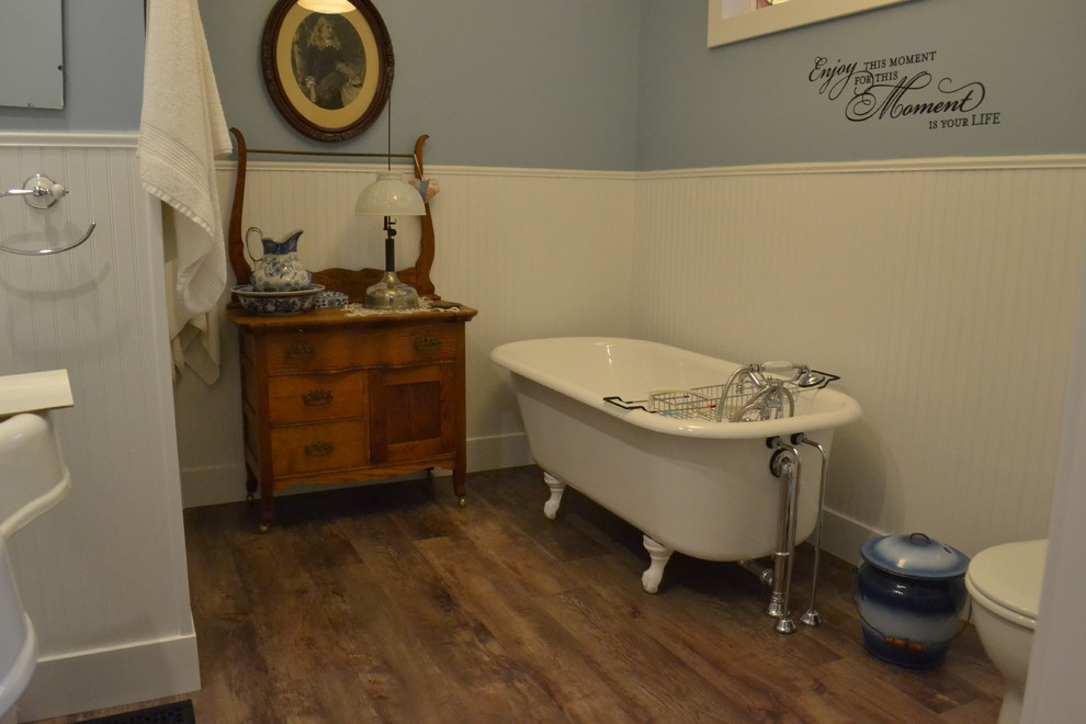 Cette image montre une douche en alcôve principale rustique de taille moyenne avec un placard à porte affleurante, des portes de placard blanches, une baignoire sur pieds, WC séparés, un mur bleu, un sol en vinyl et un lavabo de ferme.